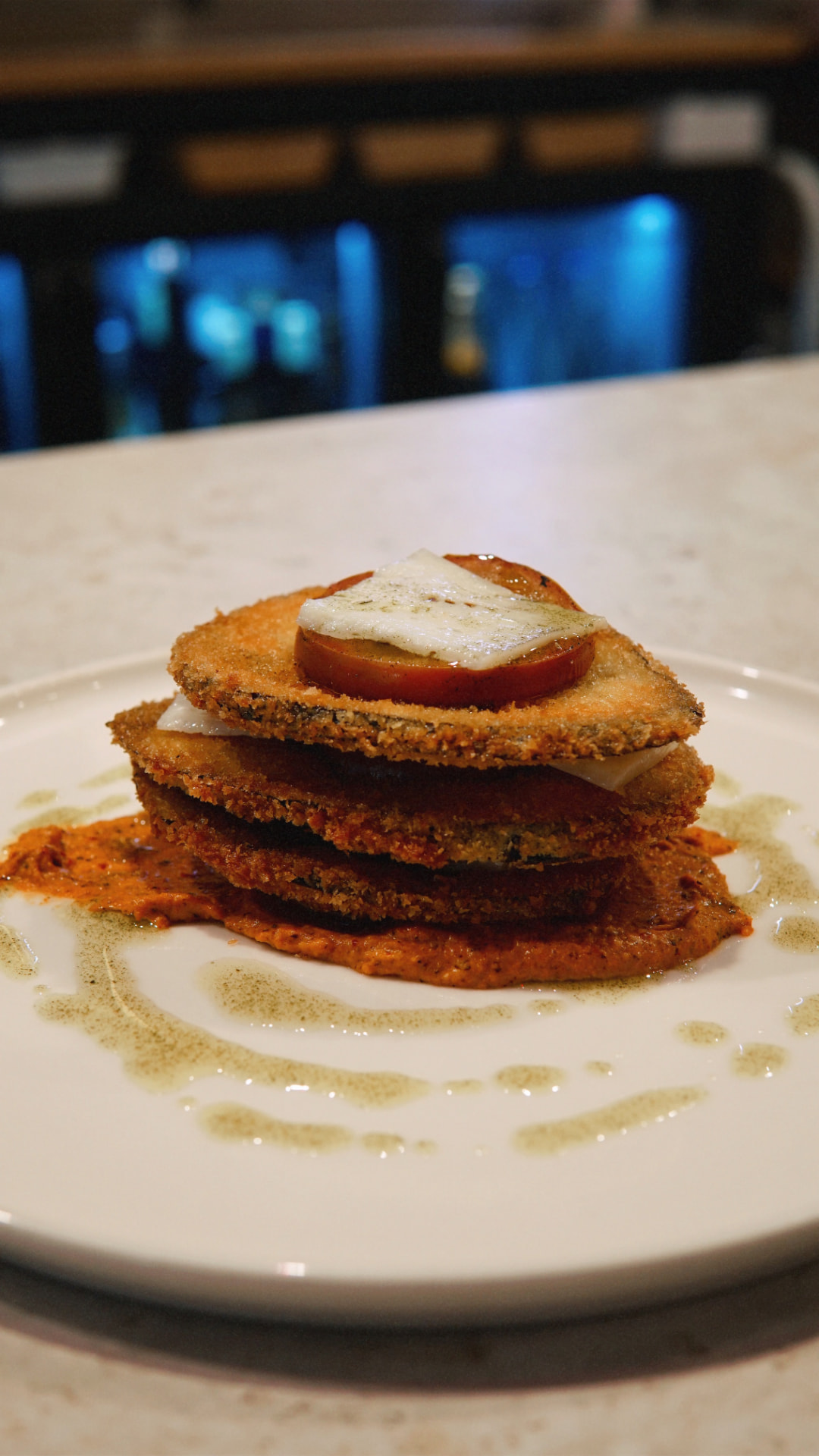 Berenjena en panko sobre romesco y aceite de menta